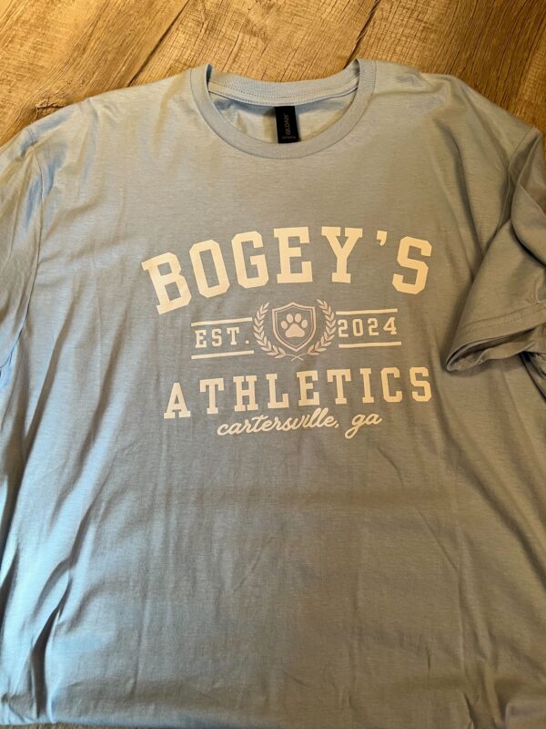 Light blue t-shirt with a white collegiate-style "Bogey's Athletics" logo, featuring a paw print crest and "Est. 2024 Cartersville, GA" text.