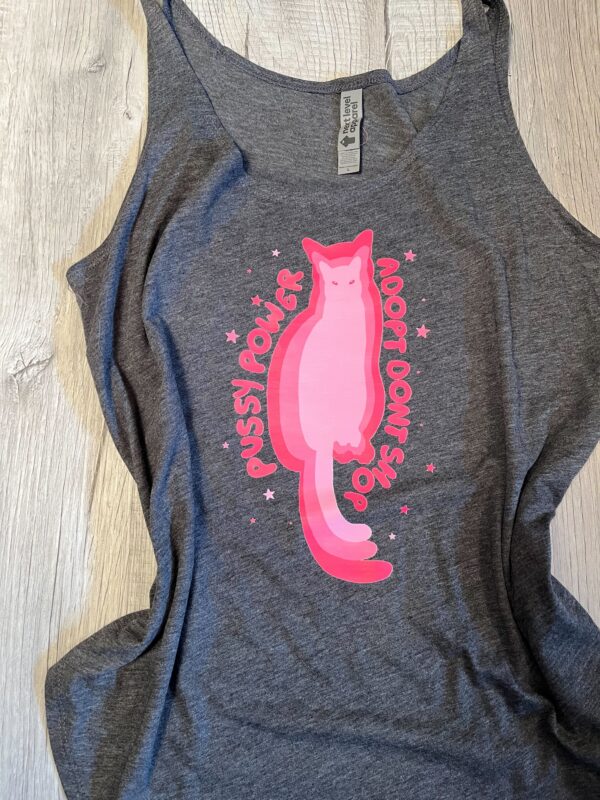 A graphic design of a multi-tonal pink cat silhouette centered between the pink hand-lettered words "Pussy Power" and "Adopt Don't Shop" with small pink stars scattered around the design.